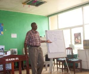 Sylvester teaching youths in a traning room in the early years of Develop Africa.